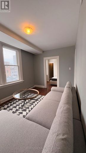 Oshawa (O'neill) apartment for rent - A living room with a grey couch and a black and white checkered floor.