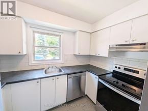 London East (East H) townhouse for rent - A kitchen with white cabinets and black countertops.
