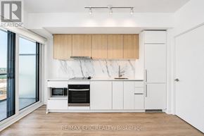 Toronto (York University Heights) condo for rent - A modern kitchen with white cabinets and a marble backsplash.