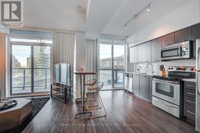 Toronto (Waterfront Communities) condo for rent - A modern kitchen with dark wood floors and stainless steel appliances.