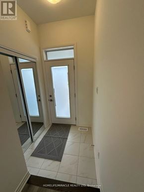 Barrie townhouse for rent - A hallway with a rug on the floor and a door on the left.