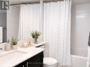 Toronto (Niagara) condo for rent - A white bathroom with a toilet, sink, and shower curtain.