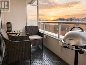 Toronto (Niagara) condo for rent - A balcony with a chair and table with a sunset in the background.