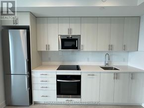 Oshawa (Windfields) condo for rent - A kitchen with white cabinets and a stainless steel refrigerator.