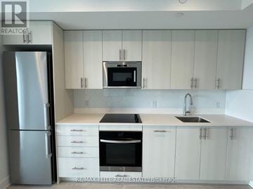 Oshawa (Windfields) condo for rent - A kitchen with white cabinets and a stainless steel refrigerator.