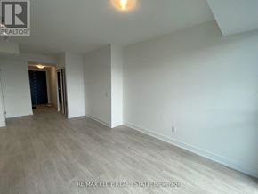 Oshawa (Windfields) condo for rent - A spacious room with a light on the ceiling and a door on the left.