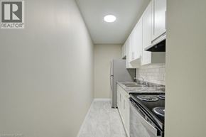 Cambridge apartment for rent - A small kitchen with white cabinets and a stove top oven.