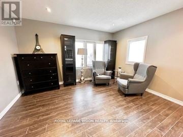 Richmond Hill (Westbrook) apartment for rent - A living room with a wooden floor and furniture including a black dresser, a grey armchair, and a black cabinet.