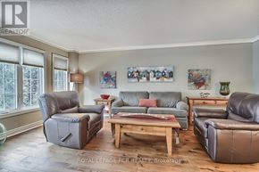 Newmarket (Stonehaven-Wyndham) apartment for rent - A living room with a grey couch, a brown leather chair, a wooden coffee table, and a painting on the wall.