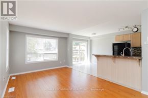 Hamilton (Binbrook) townhouse for rent - A large, empty room with wooden floors and a kitchenette in the background.