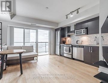 Toronto (Yonge-Eglinton) condo for rent - A modern kitchen with a dining table and a view of the city.