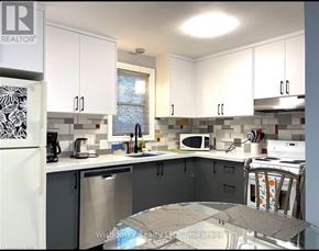 Niagara Falls (Cherrywood) duplex for rent - A kitchen with white cabinets and a marble table.