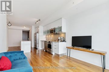 Toronto (Bay Street Corridor) condo for rent - A modern living room with a blue sofa and a television on a wooden stand.