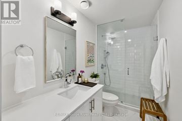 Cobourg triplex for rent - A bathroom with a white counter top and a glass shower stall.