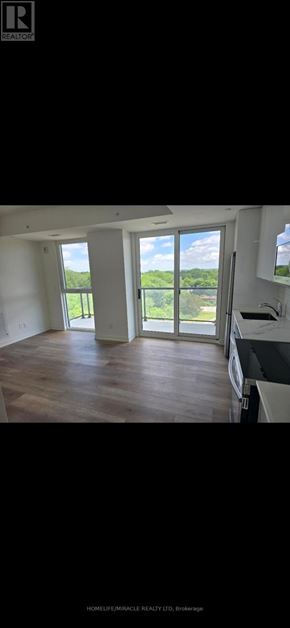 Brantford condo for rent - A spacious, well-lit room with wooden floors and large windows.