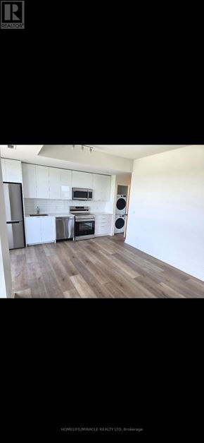 Brantford condo for rent - A modern kitchen with white cabinets and a wooden floor.