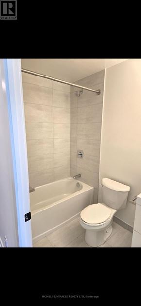 Brantford condo for rent - A white toilet is in a bathroom with a white tub and a shower.