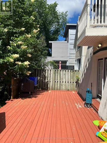 Ottawa apartment for rent - A red wooden deck with a blue stroller and a white building in the background.