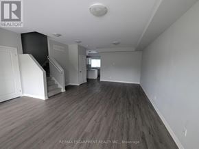 Welland (Broadway) townhouse for rent - A spacious room with wood flooring and white walls.