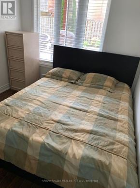 Newmarket (Woodland Hill) apartment for rent - A bed with a blue and beige comforter is in a room with a window.
