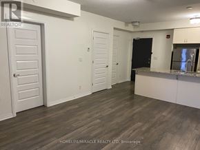 Markham (Cornell) condo for rent - A room with a white door, a black door, and a counter with a fridge.