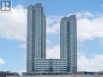 Vaughan (Brownridge) condo for rent - Two tall buildings with balconies are under a blue sky with clouds.