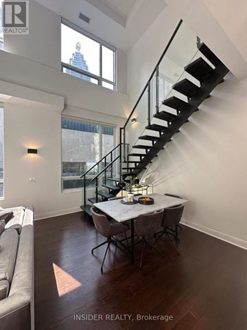 Toronto (Waterfront Communities) condo for rent - A modern living room with a glass table and a metal staircase.