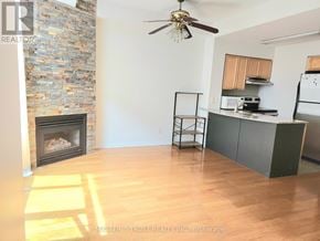 Toronto (Niagara) townhouse for rent - A room with a stone fireplace and a ceiling fan.
