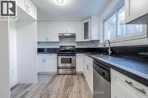 Welland (West Welland) apartment for rent - A modern kitchen with white cabinets and a stainless steel stove top.