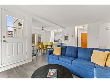 Gatineau (Hull) condo for rent - A blue couch with yellow pillows is in the foreground of a bright living room.