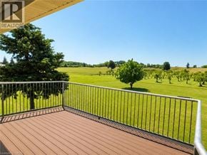 Hamilton apartment for rent - A wooden deck with a metal railing overlooks a green field.