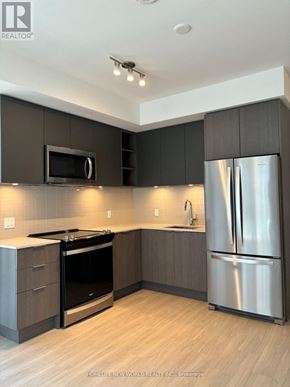 Toronto (Mount Pleasant West) condo for rent - A modern kitchen with a stainless steel refrigerator and a flat screen TV mounted above the cabinets.