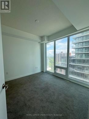 Toronto (Humber Heights) condo for rent - A room with a carpet floor and a large window overlooking a city.