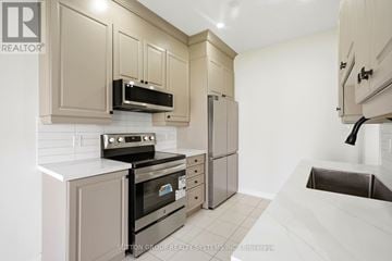 Thorold (Thorold Downtown) townhouse for rent - A kitchen with a stove top oven, microwave, and refrigerator.