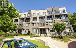 Mississauga (Erin Mills) townhouse for rent - A modern apartment building with a green lawn and picnic tables in front.