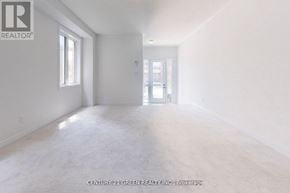 Oshawa (Kedron) apartment for rent - A spacious room with white walls and flooring, and a door at the end.