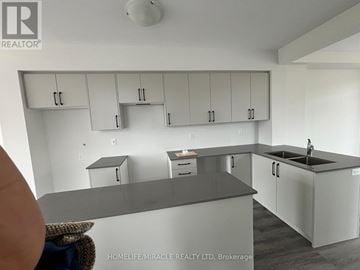 Cambridge townhouse for rent - A kitchen with white cabinets and a grey countertop.