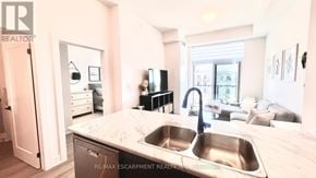 Hamilton (Waterdown) condo for rent - A kitchen with a sink and a woman standing in the background.