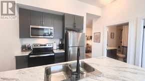 Hamilton (Waterdown) condo for rent - A modern kitchen with a marble countertop and stainless steel appliances.