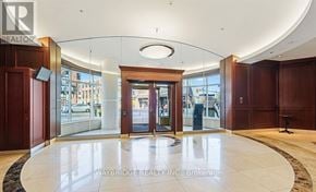Ottawa condo for rent - The image shows the lobby of a building with a large marble floor, wooden doors, and a glass window overlooking a street.