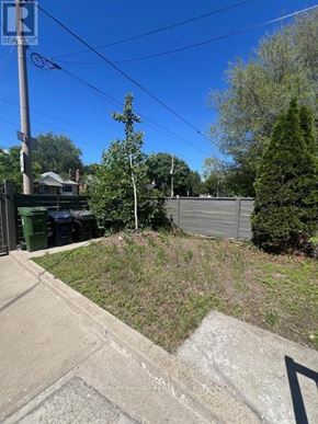 Toronto (East York) triplex for rent - A residential area with a green trash bin and a grey fence.