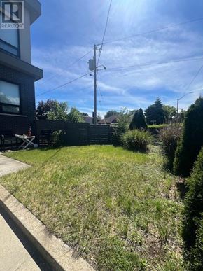 Toronto (East York) triplex for rent - A grassy area in front of a building with a sign that says REALTOR.