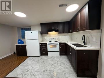 Brampton (Westgate) apartment for rent - A kitchen with white appliances and dark wood cabinets.