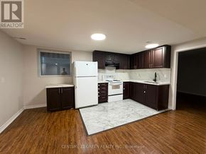 Brampton (Westgate) apartment for rent - A kitchen with white appliances and dark wood cabinets.