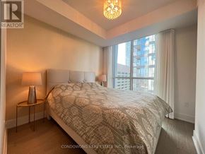 Toronto (Annex) condo for rent - A bedroom with a large bed and a chandelier.
