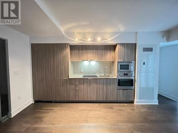 Toronto (Bay Street Corridor) condo for rent - A modern kitchen with wooden cabinets and a microwave above the oven.