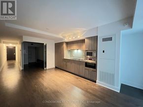 Toronto (Bay Street Corridor) condo for rent - A modern kitchen with wooden floors and white walls.
