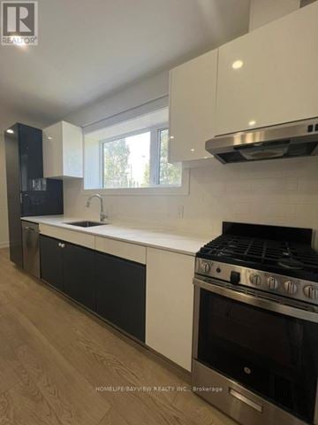 Toronto (East York) triplex for rent - A modern kitchen with a stainless steel oven and black and white cabinetry.