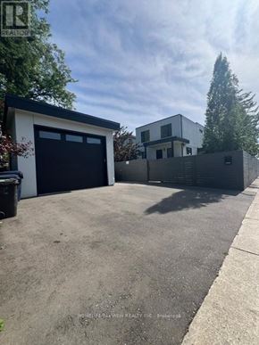 Toronto (East York) triplex for rent - A modern house with a black garage door is for sale.