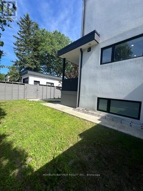 Toronto (East York) triplex for rent - A modern house with a white exterior and a black roof.